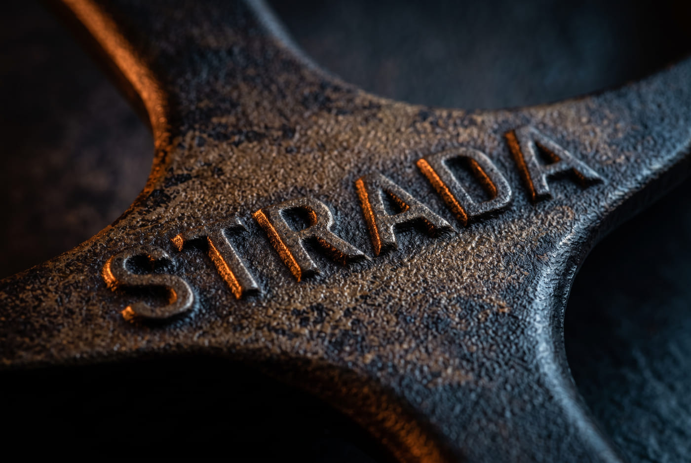 Macro detail of a seasoned cast iron handle showing the raised STRADA mark